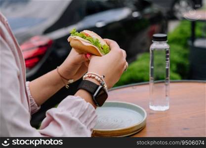 woman eating burger sandwich at outdoor terrace bistro