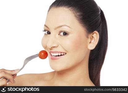 Woman eating cherry tomato on fork