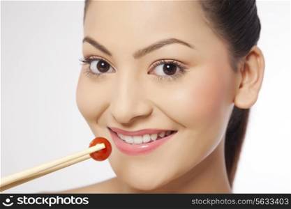 Woman eating cherry tomato with chop sticks