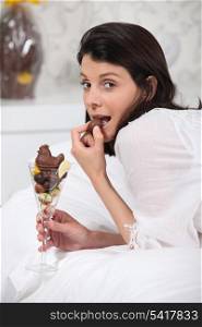 Woman eating chocolate in bed