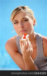 Woman eating cracker based snack by the pool