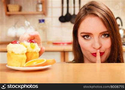 Woman eating delicious gourmet sweet cream cake cupcake and orange showing hand quiet sign gesture. Glutton girl having breakfast in secrecy. Appetite and gluttony concept.. Woman eating cake showing quiet sign. Gluttony.
