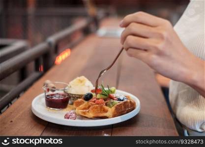 Woman eating dessert with fresh berries and fruit at cafe
