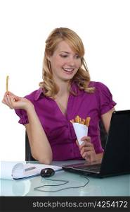 Woman eating French fries at her desk