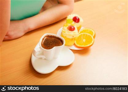Woman eating gourmet tasty cookie cake with sweet cream and fruits as dessert food on top served with orange on plate. Hot coffee beverage.. Woman with gourmet cream cake cookie and orange