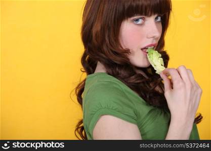 Woman eating green lettuce leaf
