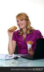 Woman eating hamburger in the office
