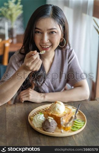woman eating honey toast, sweet dessert in the cafe