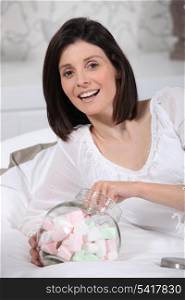 Woman eating marshmallows in bed
