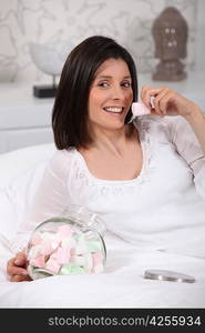 Woman eating marshmallows on her bed