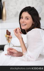 Woman eating mini Easter eggs on her bed