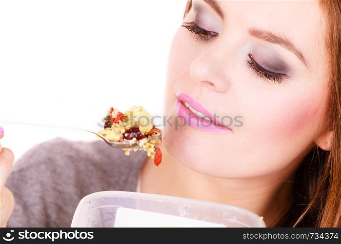Woman eating oatmeal with nuts and dried fruits for breakfast. Girl holds plastic container take homemade lunch with healthy eating. Dieting nutrition concept. Woman eat oatmeal with dry fruits. Dieting