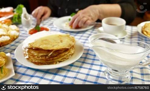 Woman eating pancakes at the table on the Pancake Day