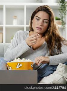 woman eating popcorn while looking laptop