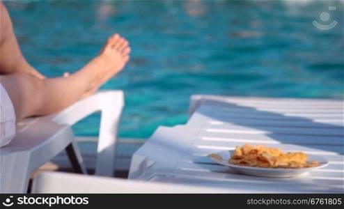 Woman eating potato chips near the swimming pool