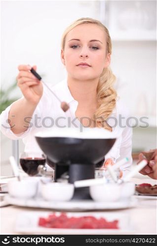 Woman eating steak fondue