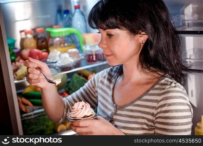 Woman eating unhealthy food from the fridge at night