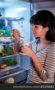 Woman eating unhealthy food from the fridge at night