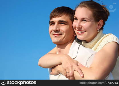 woman embraces man from behind on sky