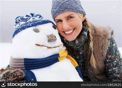 Woman embracing snowman portrait close up