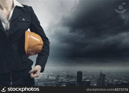 Woman engineer. Close up of businesswoman with yellow hardhat in hand