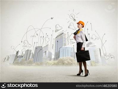 Woman engineer. Image of woman engineer in helmet with drafts. Construction concept