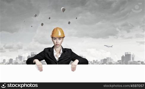 Woman engineer with banner. Attractive woman builder demonstrating white blank banner