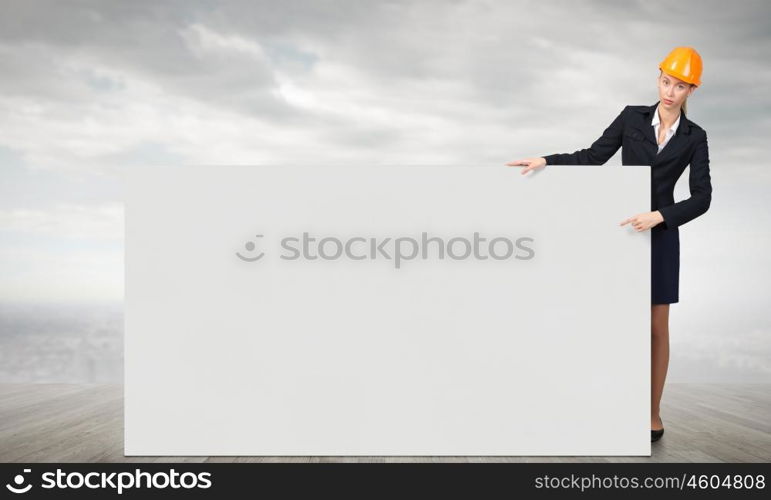 Woman engineer with banner. Attractive woman builder demonstrating white blank banner