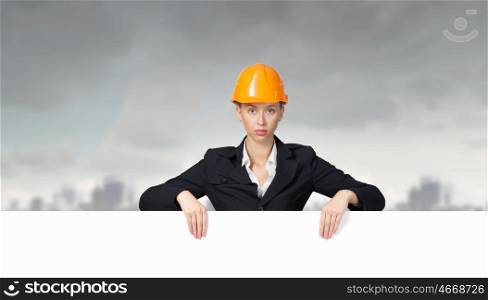 Woman engineer with banner. Attractive woman builder demonstrating white blank banner