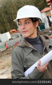 Woman engineer with white security helmet standing on construction site