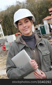 Woman engineer with white security helmet standing on construction site