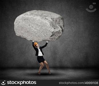 Woman engineer. Young woman engineer lifting huge stone above head