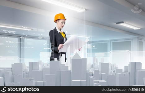 Woman engineer. Young woman in hardhat examining construction project