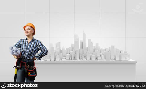 Woman engineer. Young woman in hardhat with construction project in hands