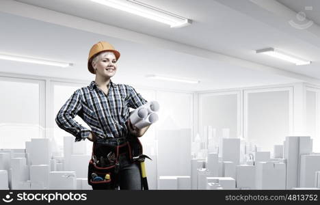 Woman engineer. Young woman in hardhat with construction project in hands