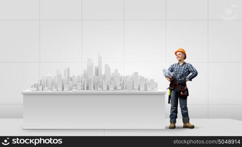 Woman engineer. Young woman in hardhat with construction project in hands