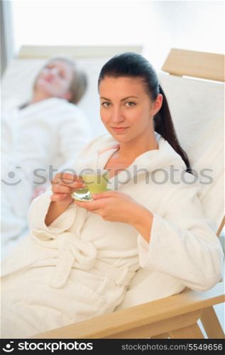 Woman enjoy coffee at beauty spa with friend in background