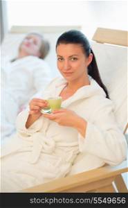 Woman enjoy coffee at beauty spa with friend in background