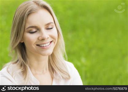 Woman enjoy nature. A beautiful young woman on grass enjoy nature smiling with closed eyes