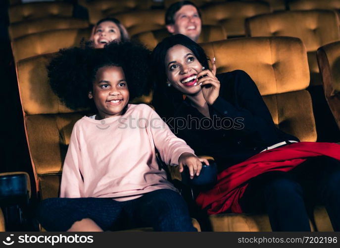 Woman enjoy to watch a movie with her daughter at the cinema smiling and laughing together