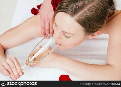 Woman enjoying a back massage in a spa setting drinking a glass of champagne