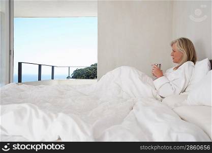 Woman Enjoying a Beverage in Bed