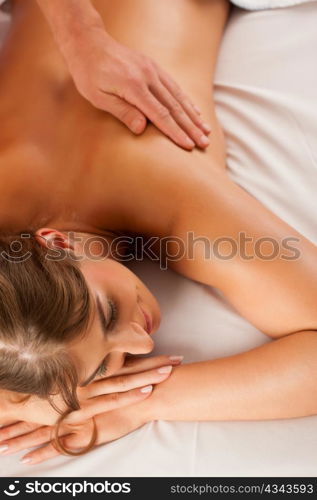 Woman enjoying a wellness back massage in a spa, she is very relaxed (close-up)