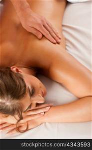 Woman enjoying a wellness back massage in a spa, she is very relaxed (close-up)