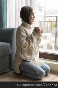 woman enjoying cup coffee window home during pandemic