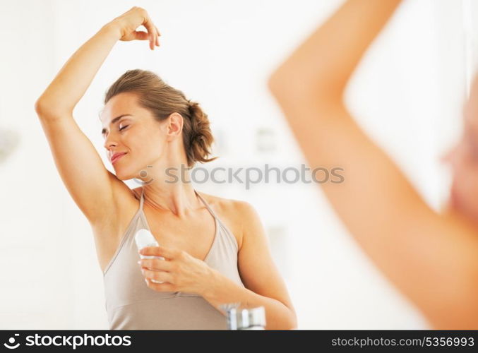 Woman enjoying freshness after applying roller deodorant on underarm