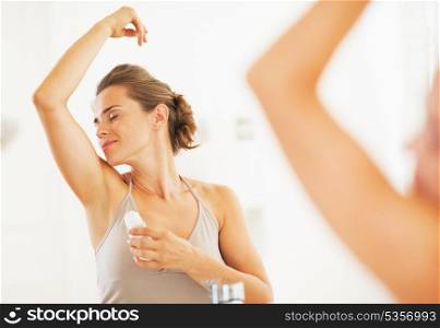 Woman enjoying freshness after applying roller deodorant on underarm