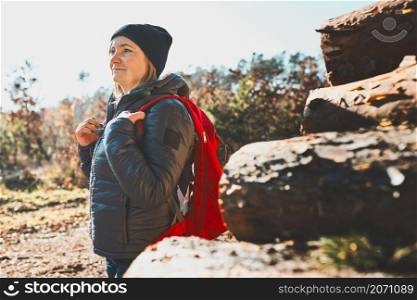 Woman enjoying hike on sunny vacation day. Female with backpack walking through forest. Spending summer vacation close to nature
