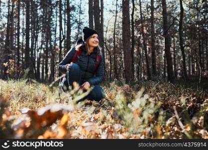 Woman enjoying hike on sunny vacation day. Female with backpack walking through forest path. Spending summer vacation close to nature