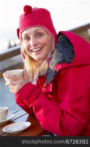 Woman Enjoying Hot Drink In Cafe At Ski Resort